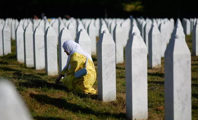 A woman mourns next to the grave of her relative, victim of the Srebrenica genocide, at the Memorial Center in Potocari, Bosnia, Friday, July 11, 2025. (AP Photo/Darko Bandic)