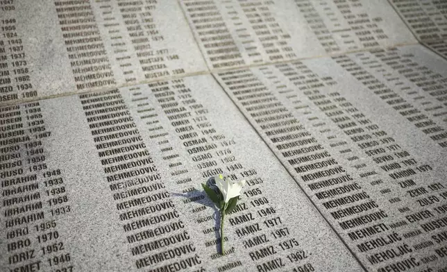 A flower is seen on a monument with the names of those killed in Srebrenica genocide, at the Memorial Center in Potocari, Bosnia, Friday, July 11, 2025. (AP Photo/Armin Durgut)