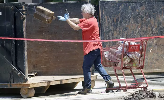 A worker tosses damaged merchandise into a large dumpster at the Trader Joe's supermarket in the Eastgate shopping center after it was flooded out during tropical storm Chantal, Monday, July 7, 2025, in Chapel Hill, N.C. (AP Photo/Chris Seward)
