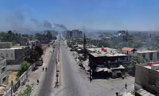 Bedouin fighters deploy at Mazraa village on the outskirts of Sweida city, as smoke rise from the clashes between the Bedouin clans and Druze militias, southern Syria, Friday, July 18, 2025. (AP Photo/Ghaith Alsayed)