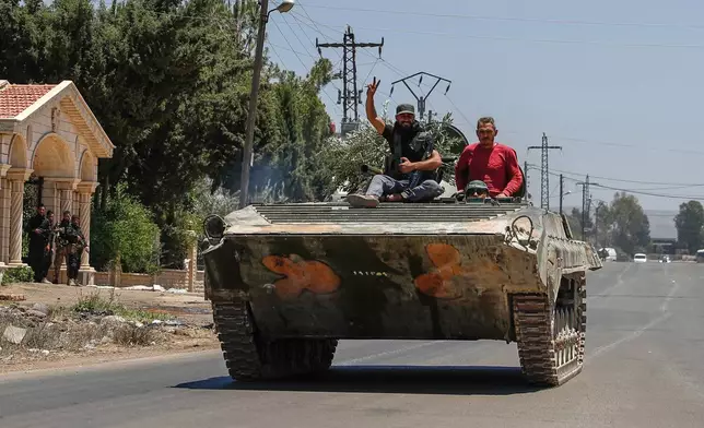 Syrian government forces sit on their armored personnel carrier, as they withdraw from Sweida city, southern Syria, Tuesday, July 15, 2025.(AP Photo/Ghaith Alsayed)