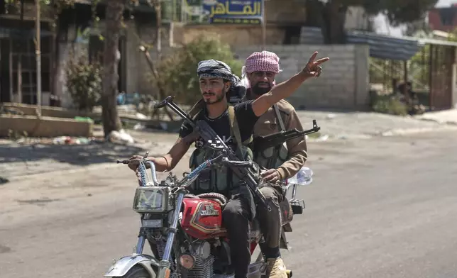 A Bedouin fighter flashes victory sign as he rides a motorcycle at Mazraa village on the outskirts of Sweida city, where clashes erupted between theBedouin clans and Druze militias, southern Syria, Friday, July 18, 2025. (AP Photo/Ghaith Alsayed)