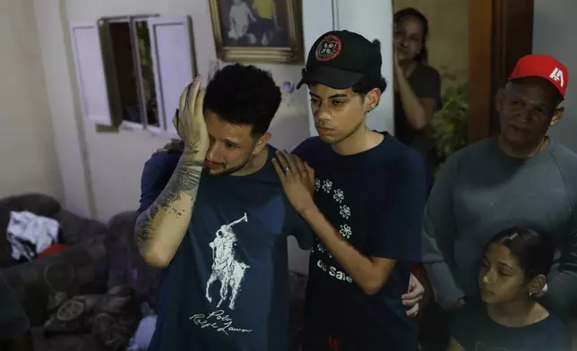 Arturo Suárez, left, a musician, one of the Venezuelan migrants deported months ago to El Salvador by the United States under the U.S. President Donald Trump administration's immigration crackdown, reacts as he returned home and was welcomed by his relatives in Caracas, Venezuela, Tuesday, July 22, 2025. (AP Photo/Cristian Hernandez)