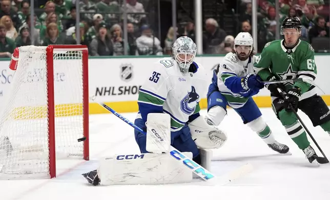 FILE - Vancouver Canucks goaltender Thatcher Demko (35) watches a shot go wide of the net as Conor Garland (8) helps against pressure from Dallas Stars right wing Evgenii Dadonov (63) in the first period of an NHL hockey game in Dallas, April 8, 2025. (AP Photo/LM Otero, File)