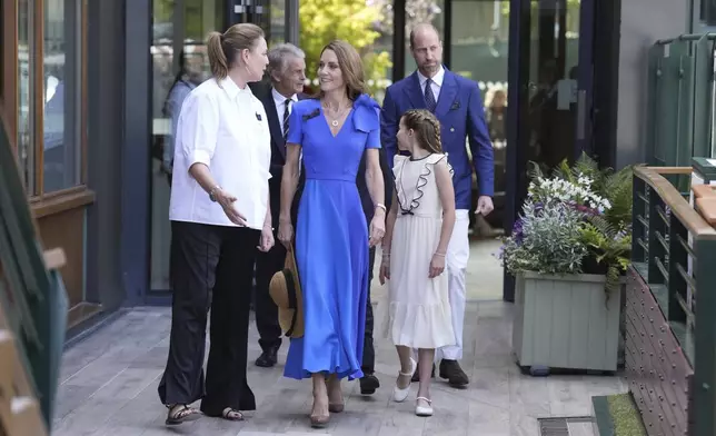 Britain's Prince William, Kate, Princess of Wales, center, and Princess Charlotte are greeted by Sally Ambrose, left, a member of the Committee of Management of The Championships, as they arrive to attend the men's singles final match between Italy's Jannik Sinner and Spain's Carlos Alcaraz at the Wimbledon Tennis Championships in London Sunday July 13, 2025. (Andrew Matthews/Pool via AP)