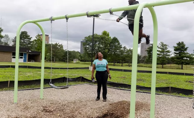 Adrienne Hazel watches her son Ricky as he plays on a swing on Thursday, July 17, 2025, in Southfield, Mich. (AP Photo/Sylvia Jarrus)