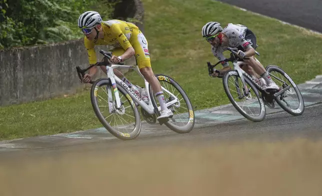 Slovenia's Tadej Pogacar, wearing the overall leader's yellow jersey, and teammate Britain's Adam Yates ride on the Charade Circuit during the tenth stage of the Tour de France cycling race over 165.3 kilometers (102.7 miles) with start in Ennezat and finish in Le Mont-Dore Puy de Sancy, France, Monday, July 14, 2025. (AP Photo/Thibault Camus)