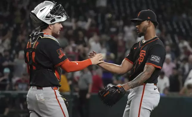 San Francisco Giants catcher Patrick Bailey (14) and pitcher Camilo Doval celebrate after defeating the Arizona Diamondbacks during a baseball game, Wednesday, July 2, 2025, in Phoenix. (AP Photo/Rick Scuteri)