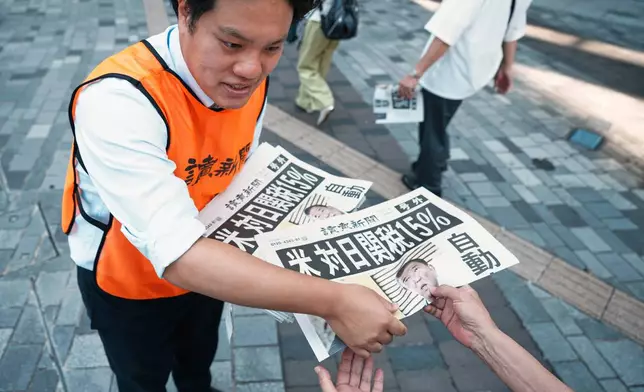 A staff member distributes an extra edition of the Yomiuri Shimbun newspaper reporting that President Donald Trump announced a trade framework with Japan on Tuesday, Wednesday, July 23, 2025, in Tokyo. (AP Photo/Eugene Hoshiko)