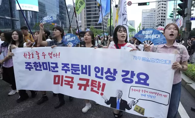 Supporters of the South Korean Confederation of Trade Unions march during a rally against the government's labor policy and U.S. President Donald Trump's tariffs policy on South Korea, in Seoul, South Korea, Saturday, July 19, 2025. The banner reads "We Condemn U.S. for forcing the the costs of station U.S. troops in South Korea!."(AP Photo/Ahn Young-joon)