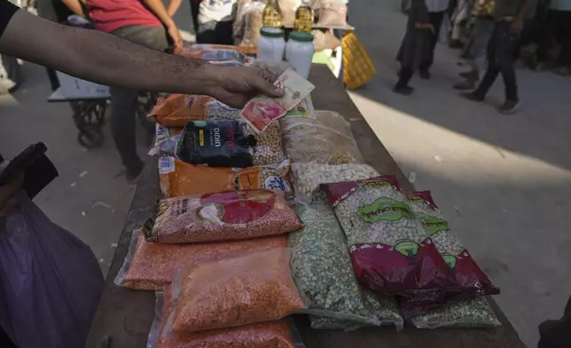 A Palestinian pays for goods at a street market in Gaza City, Wednesday, July 23, 2025. (AP Photo/Jehad Alshrafi)
