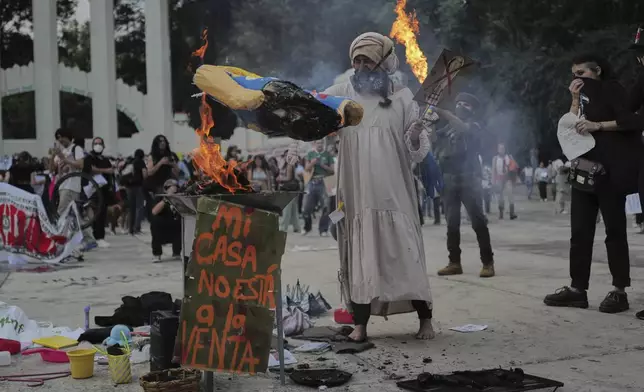 A demonstrator burns an effigy of U.S. President Donald Trump in Parque Mexico, during a protest against gentrification, as the increase in remote workers has risen prices and increased housing demand in neighborhoods like Condesa and Roma, in Mexico City, Friday, July 4, 2025. (AP Photo/Jon Orbach)