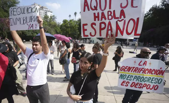 Demonstrators hold posters that read in Spanish ¨Here we speak Spanish, Real Estate Regulation Now¨, during a protest against gentrification, as the increase in remote workers has risen prices and increased housing demand in neighborhoods like Condesa and Roma, in Mexico City, Friday, July 4, 2025. (AP Photo/Fernando Llano)