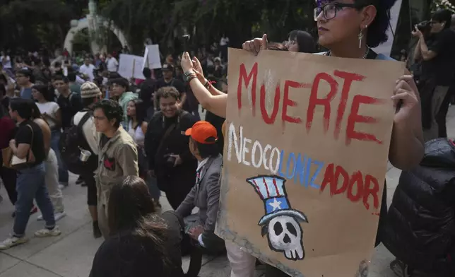 A demonstrators holds a poster with a message that reads in Spanish ¨Death to the neo-colonizer¨, during a protest against gentrification, as the increase in remote workers has risen prices and increased housing demand in neighborhoods like Condesa and Roma, in Mexico City, Friday, July 4, 2025. (AP Photo/Fernando Llano)