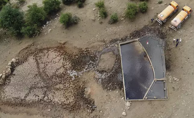 Workers used hoses to fill up the pond with water for hundreds of cows and horses during a severe drought on a mountain Suva Planina, in southeast Serbia, Thursday, July 17, 2025. (AP Photo/Darko Vojinovic)
