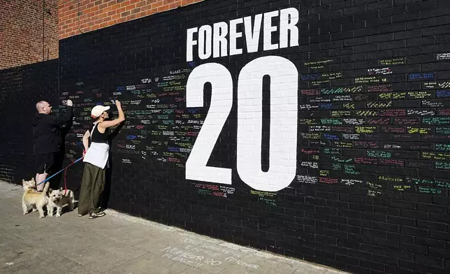 Fans sign a mural in memory of late Liverpool player Diogo Jota, on Sybil Road near Anfield in Liverpool, England, Tuesday, July 8, 2025. (Peter Byrne/PA via AP)