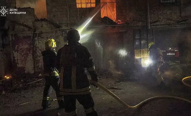 In this photo provided by the Ukrainian Emergency Service, first responders work to extinguish a fire following a Russian attack in Kyiv region, Ukraine, Friday, July 4, 2025. (Ukrainian Emergency Service via AP)