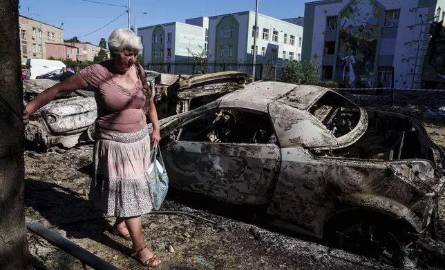A local woman walks past cars destroyed by a Russian strike in Kyiv, Ukraine, on Friday, July 4, 2025. (AP Photo/Evgeniy Maloletka)