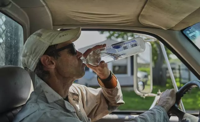 Isaac Barnes takes a drink of water after harvesting honeycomb from his honeybee hives Tuesday, June 24, 2025, in Williamsport, Ohio. (AP Photo/Joshua A. Bickel)