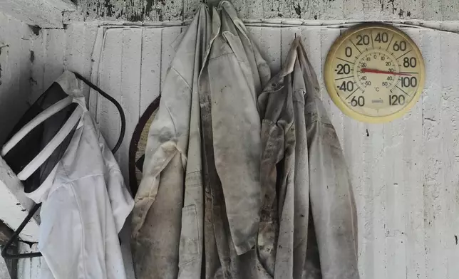 Beekeeping suits hang next to an outdoor thermometer Tuesday, June 24, 2025, at Honeyrun Farm in Williamsport, Ohio. (AP Photo/Joshua A. Bickel)