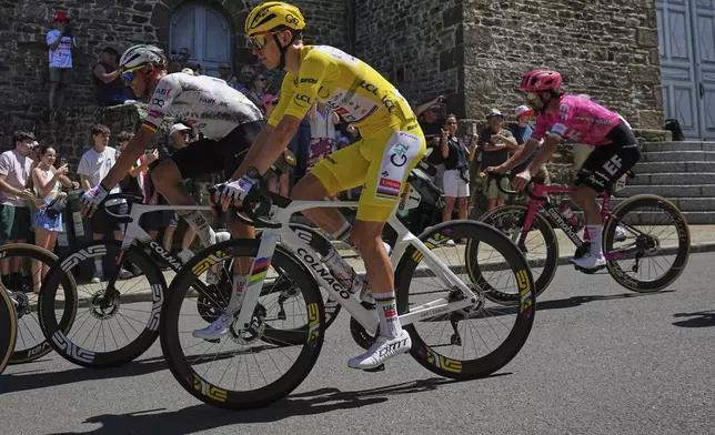 Ireland's Ben Healy, right in pink jersey, follows Slovenia's Tadej Pogacar, wearing the overall leader's yellow jersey, and Germany's Nils Politt, left, during the eighth stage of the Tour de France cycling race over 171.4 kilometers (106.5 miles) with start in Saint-Meen-le-Grand and finish in Laval Espace Mayenne, France, Saturday, July 12, 2025. (AP Photo/Thibault Camus)