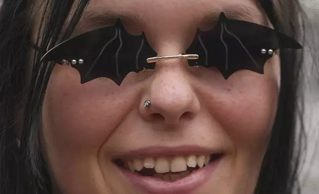 A music fan wears a sunglasses depicting bats to commemorate the death of Ozzy Osbourne at the Black Sabbath Bridge in Birmingham, Wednesday, July 23, 2025. (AP Photo/Kin Cheung)
