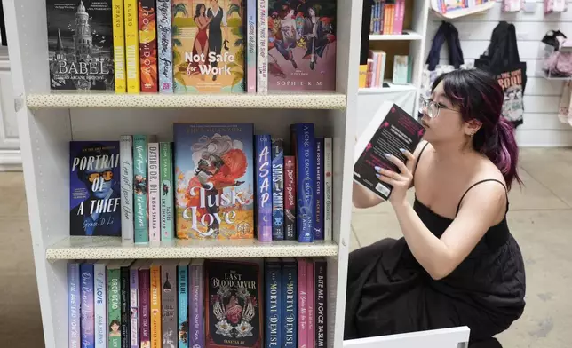 Ashley Dang, an employee at The Ripped Bodice, stocks romance titles at the bookstore in Culver City, Calif., on Thursday, July 3, 2025,. (AP Photo/Chris Pizzello)