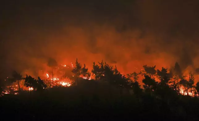 Wildfire flames engulf a forest near the town of Kasab, in Syria's Latakia countryside, early Saturday, July 12, 2025. (AP Photo/Ghaith Alsayed)