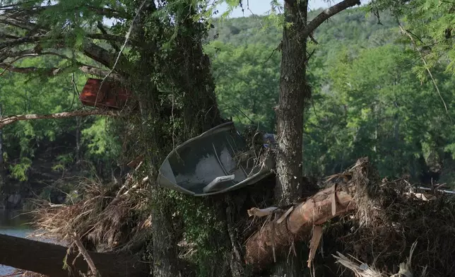 A boat and debris are stuck in damaged trees following flooding Thursday, July 10, 2025, in Ingram, Texas. (AP Photo/Joshua A. Bickel)