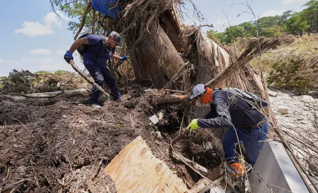Volunteer Mario Rios, right, and a fellow volunteer, search along the bank of the river after flash floods along the Guadalupe River in Kerrville, Texas, Thursday, July 10, 2025. (AP Photo/Gerald Herbert)