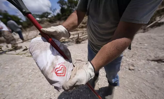 Kevin Scott shows a pair of shorts he found with "Heart of the Hills Camp" logo along the Guadalupe River after flooding in Kerrville, Texas on Wednesday , July 9, 2025. (AP Photo/Gerald Herbert)