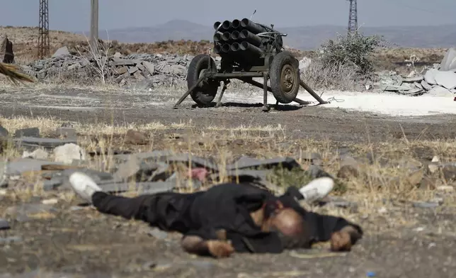 A dead fighter of the Druze militias lies on the ground in front of a rocket launcher on the outskirts of Sweida city, where clashes erupted between Sunni Bedouin clans and Druze militias, in southern Syria, Monday, July 14, 2025. (AP Photo/Omar Sanadiki)