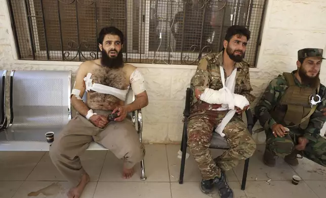 Syrian government soldiers who were injured in Sweida city during clashes between the Syrian government forces and Druze militias, sit outside a clinic after they received treatments in Busra al-Harir village, southern Syria, Tuesday, July 15, 2025. (AP Photo/Omar Albam)