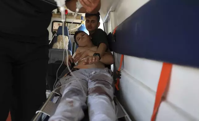A boy who was injured in Sweida city during clashes between the Syrian government forces and Druze militias, lies inside an ambulance in Busra al-Harir village, southern Syria, Tuesday, July 15, 2025. (AP Photo/Omar Albam)