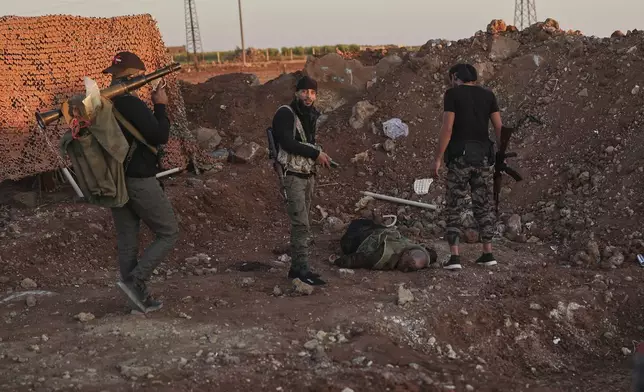 Syrian government forces stand next of a dead fighter from Druze militias, at Mazraa village on the outskirts of the city of Sweida, where clashes erupted between Sunni Bedouin clans and Druze militias, southern Syria, Monday, July 14, 2025. (AP Photo/Ghaith Alsayed)