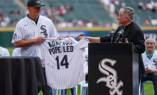 Cardinal Blase Cupich, right, presents former White Sox player Paul Konerko with a jersey signed by Pope Leo XIV during a ceremony honoring the 2005 World Series Champions before a baseball game between the Cleveland Guardians and Chicago White Sox, Saturday, July 12, 2025, in Chicago. (AP Photo/Erin Hooley)