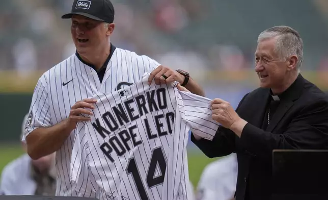 Cardinal Blase Cupich, right, presents former White Sox player Paul Konerko with a jersey signed by Pope Leo XIV during a ceremony honoring the 2005 World Series Champions before a baseball game between the Cleveland Guardians and Chicago White Sox, Saturday, July 12, 2025, in Chicago. (AP Photo/Erin Hooley)