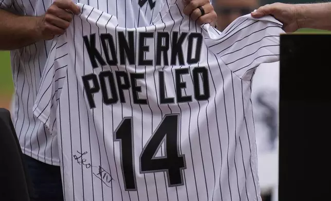 Cardinal Blase Cupich, right, presents former Chicago White Sox player Paul Konerko with a jersey signed by Pope Leo XIV during a ceremony honoring the 2005 World Series Champions before a baseball game between the Cleveland Guardians and Chicago White Sox, Saturday, July 12, 2025, in Chicago. (AP Photo/Erin Hooley)