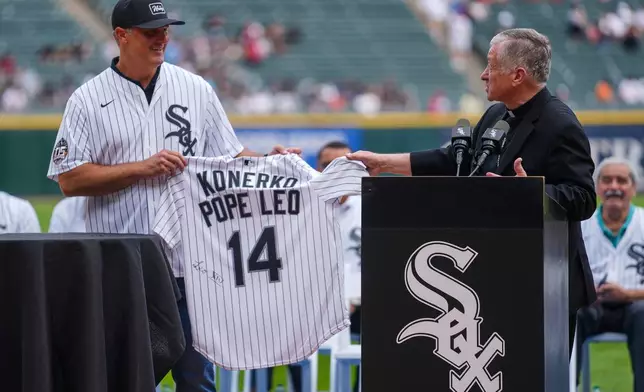 Cardinal Blase Cupich, right, presents former White Sox player Paul Konerko with a jersey signed by Pope Leo XIV during a ceremony honoring the 2005 World Series Champions before a baseball game between the Cleveland Guardians and Chicago White Sox, Saturday, July 12, 2025, in Chicago. (AP Photo/Erin Hooley)