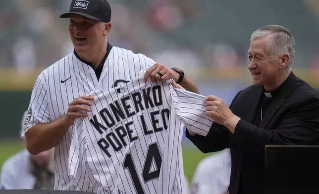 Cardinal Blase Cupich, right, presents former White Sox player Paul Konerko with a jersey signed by Pope Leo XIV during a ceremony honoring the 2005 World Series Champions before a baseball game between the Cleveland Guardians and Chicago White Sox, Saturday, July 12, 2025, in Chicago. (AP Photo/Erin Hooley)