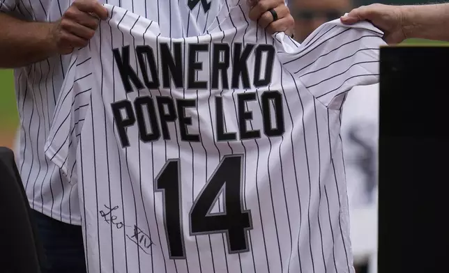 Cardinal Blase Cupich, right, presents former Chicago White Sox player Paul Konerko with a jersey signed by Pope Leo XIV during a ceremony honoring the 2005 World Series Champions before a baseball game between the Cleveland Guardians and Chicago White Sox, Saturday, July 12, 2025, in Chicago. (AP Photo/Erin Hooley)