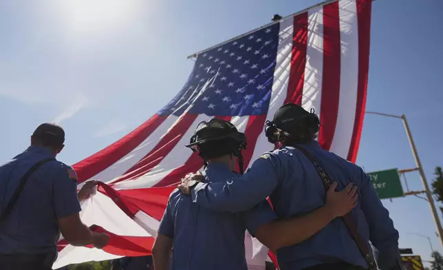 The Coeur d'Alene Fire Dept. hangs an American flag to honor the firefighters who were killed Sunday, in Coeur d'Alene, Idaho, on Tuesday, July 1, 2025. (AP Photo/Lindsey Wasson)