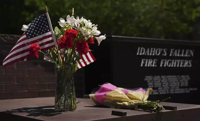 Flowers are seen at the Fallen Heroes Plaza at Cherry Hill Park near the scene the day after a shooter ambushed and killed firefighters responding to a wildfire at Canfield Mountain Monday, June 30, 2025, in Coeur D'Alene, Idaho. (AP Photo/Lindsey Wasson)