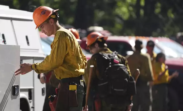 A firefighter with the United States Forest Service prepares gear at a staging area near the scene the day after a shooter ambushed and killed multiple firefighters responding to a wildfire at Canfield Mountain Monday, June 30, 2025, in Coeur D'Alene, Idaho. (AP Photo/Lindsey Wasson)