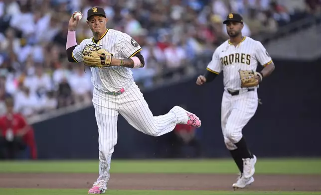 San Diego Padres third baseman Manny Machado, left, throws to first base on a groundout ht by Philadelphia Phillies' Edmundo Sosa to end the top of the seventh inning in a baseball game Saturday, July 12, 2025, in San Diego. (AP Photo/Orlando Ramirez)