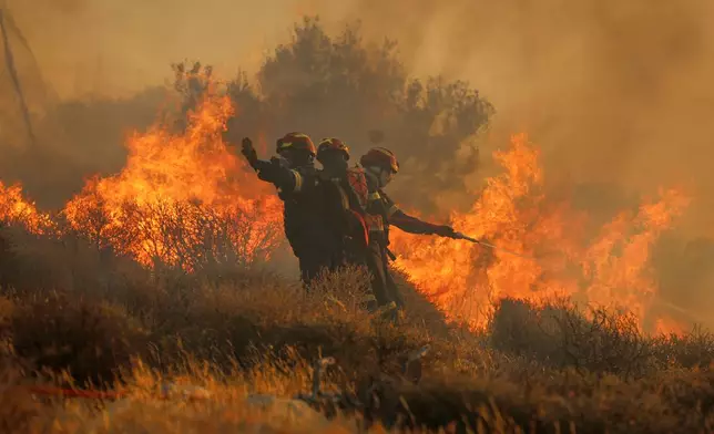 Firefighter uses a hose as the try to extinguish the blaze near the town of Ierapetra on the south coast of Crete island, Greece, Thursday July 3, 2025, as a fast-moving wildfire prompted authorities to clear villages and coastal areas, officials said. (InTime News via AP)