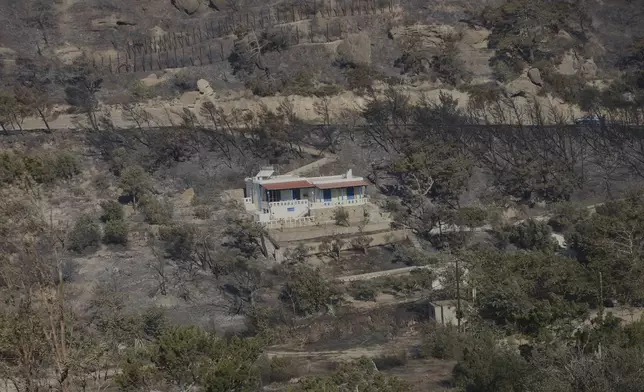 A house lies among scorched trees near the town of Ierapetra on the south coast of Crete island, Greece, Thursday, July 3, 2025, after a fast-moving wildfire prompted the evacuation of villages and coastal areas, officials said. (InTime News via AP)