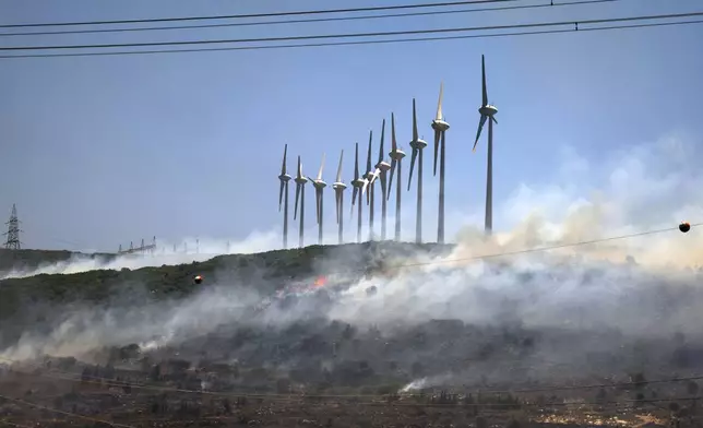 A fire rages near windmills in Cesme, near Izmir, Turkey, Thursday, July 3, 2025. (Cengiz Malgir/Dia Photo via AP)