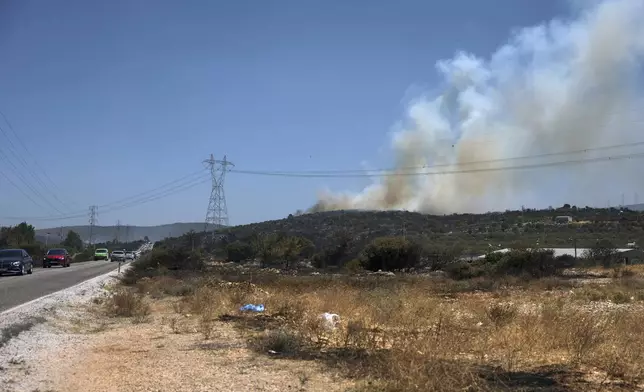 Cars drive past a fire in Cesme, near Izmir, Turkey, Thursday, July 3, 2025. (Cengiz Malgir/Dia Photo via AP)