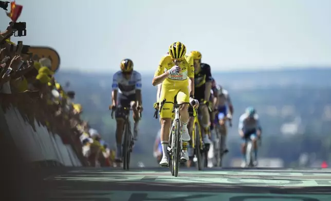 Slovenia's Tadej Pogacar wearing the overall leader's yellow jersey crosses the finish line during the sixth stage of the Tour de France cycling race over 201.5 kilometers (125.2 miles) with start in Bayeux and finish in Vire Normandy, France, Thursday, July 10, 2025. (AP Photo/Mosa'ab Elshamy)